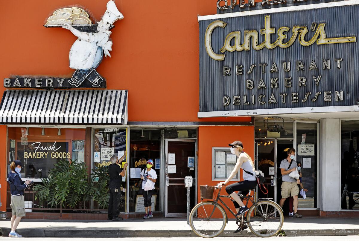 A bicyclist and a few pedestrians outside Canter's Deli