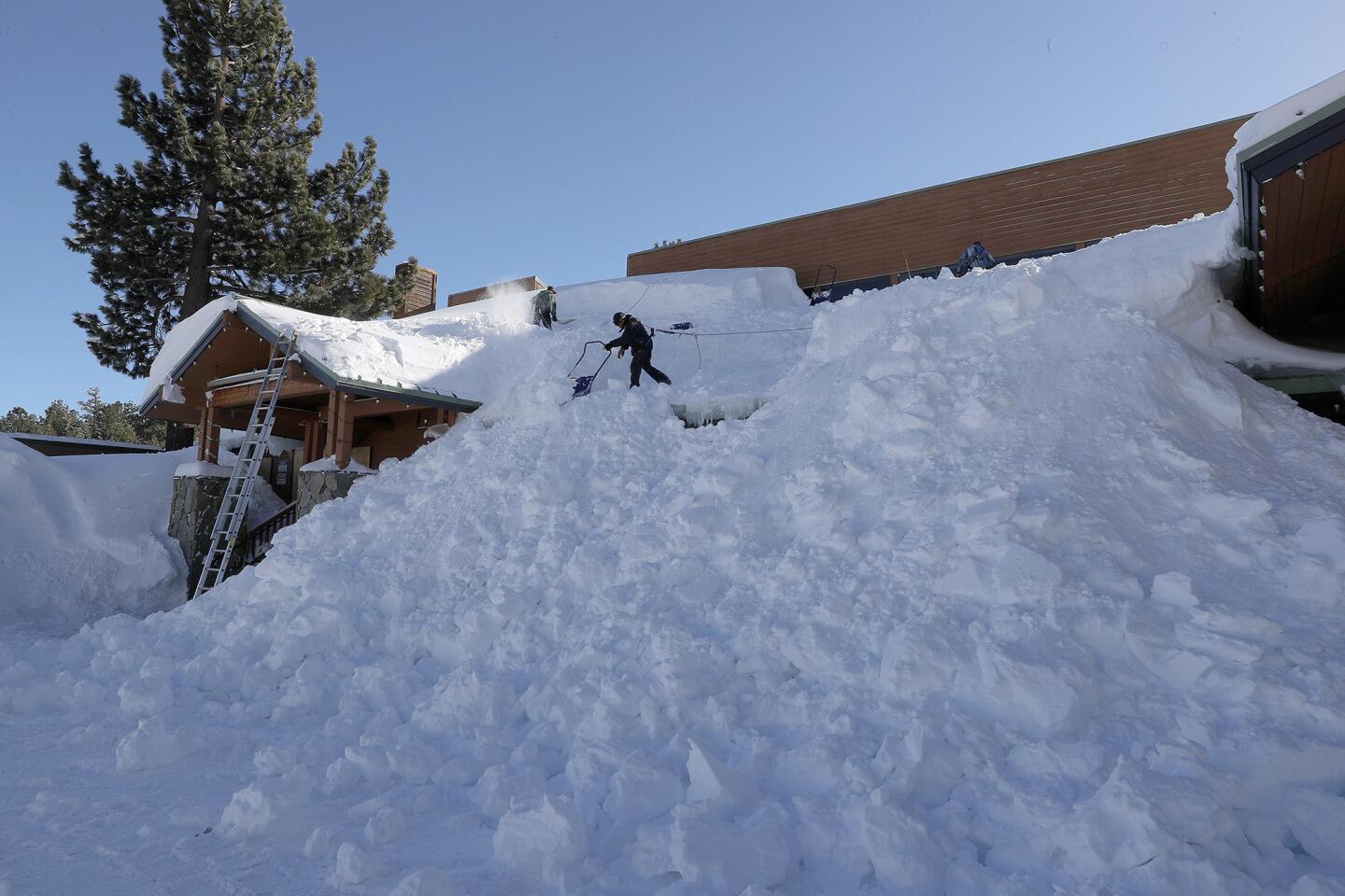 Workers shovel giant snowdrifts off the roof of the Mammoth Luxury Outlets in Mammoth Lakes on Feb. 6 after a blizzard dropped as much as 10 feet of snow.