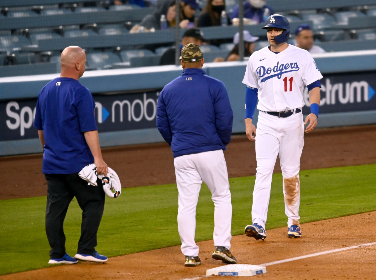 Dodgers baserunner AJ Pollock tests his hamstring in front of Dodgers manager Dave Roberts and a team trainer.