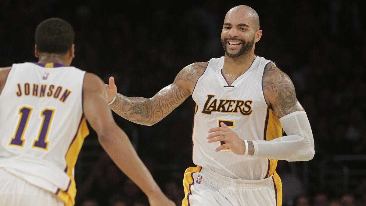 Lakers forward Carlos Boozer, right, celebrates with teammate Wesley Johnson after scoring a basket during the second half of a 129-122 overtime win against the Toronto Raptors at Staples Center on Sunday.