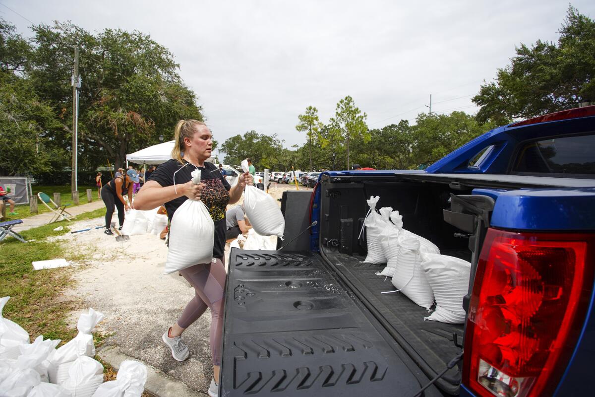 A woman loads sandbags into her truck.