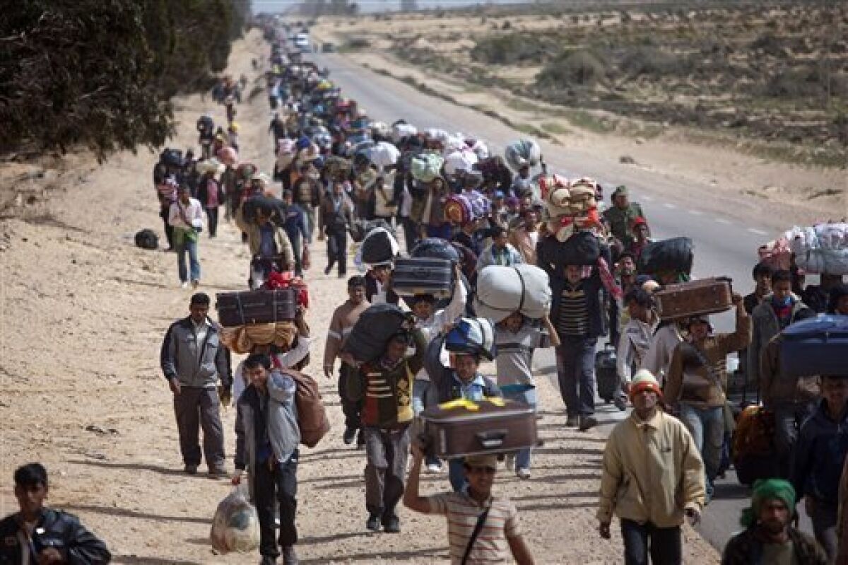 Men from Bangladesh, who used to work in Libya but recently fled the unrest, walk with their belongings alongside a road, as they head to a refugee camp after crossing the Tunisia-Libyan border, in Ras Ajdir, Tunisia, Friday, March 4, 2011. (AP Photo/Emilio Morenatti)