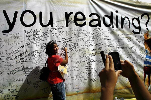 Brittany Carr, 17, left, poses for her sister Lauren, 19, after signing the "What are You Reading?" wall during the Los Angeles Times Festival of Books at UCLA.