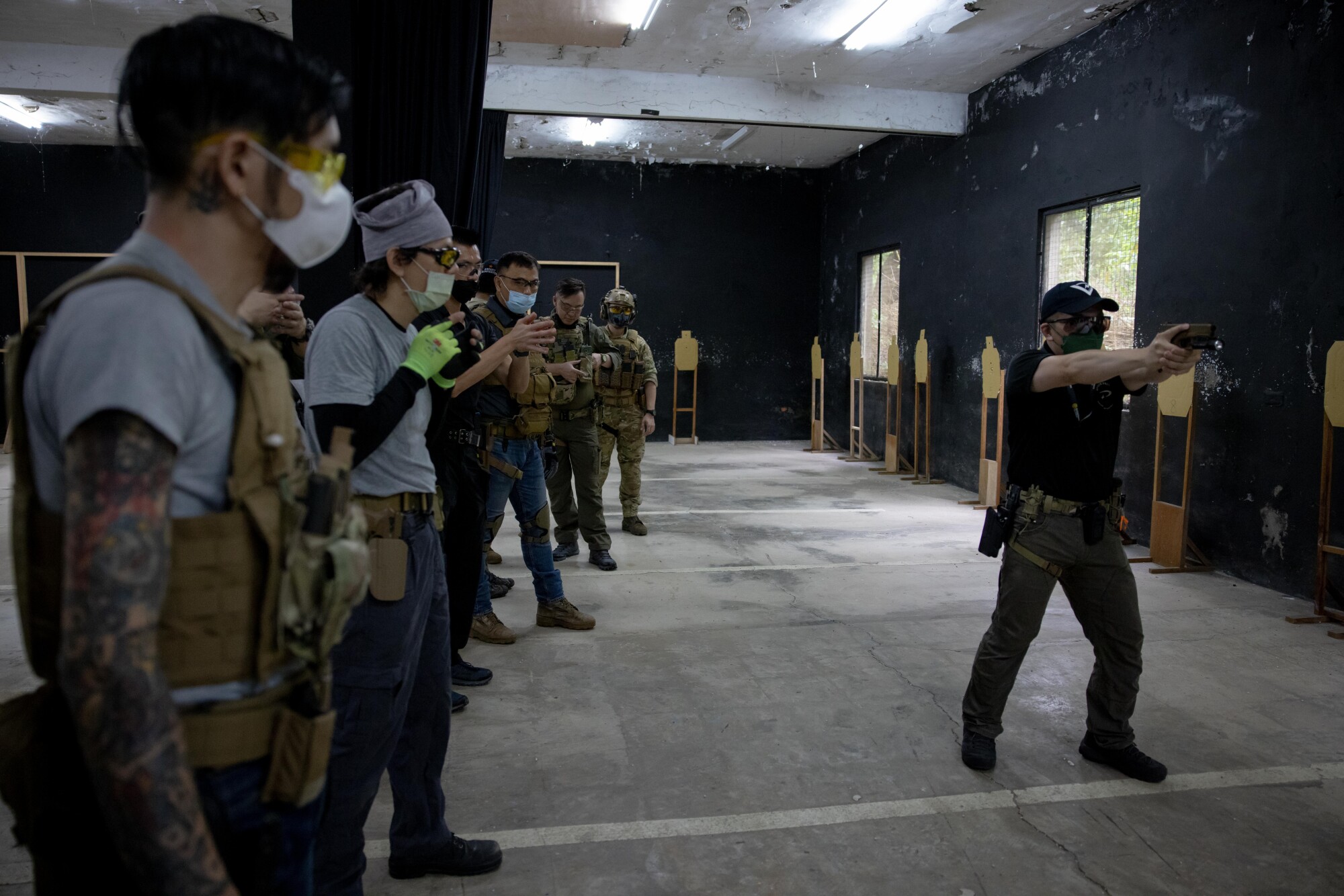 A row of people watch a man shoots a weapon.