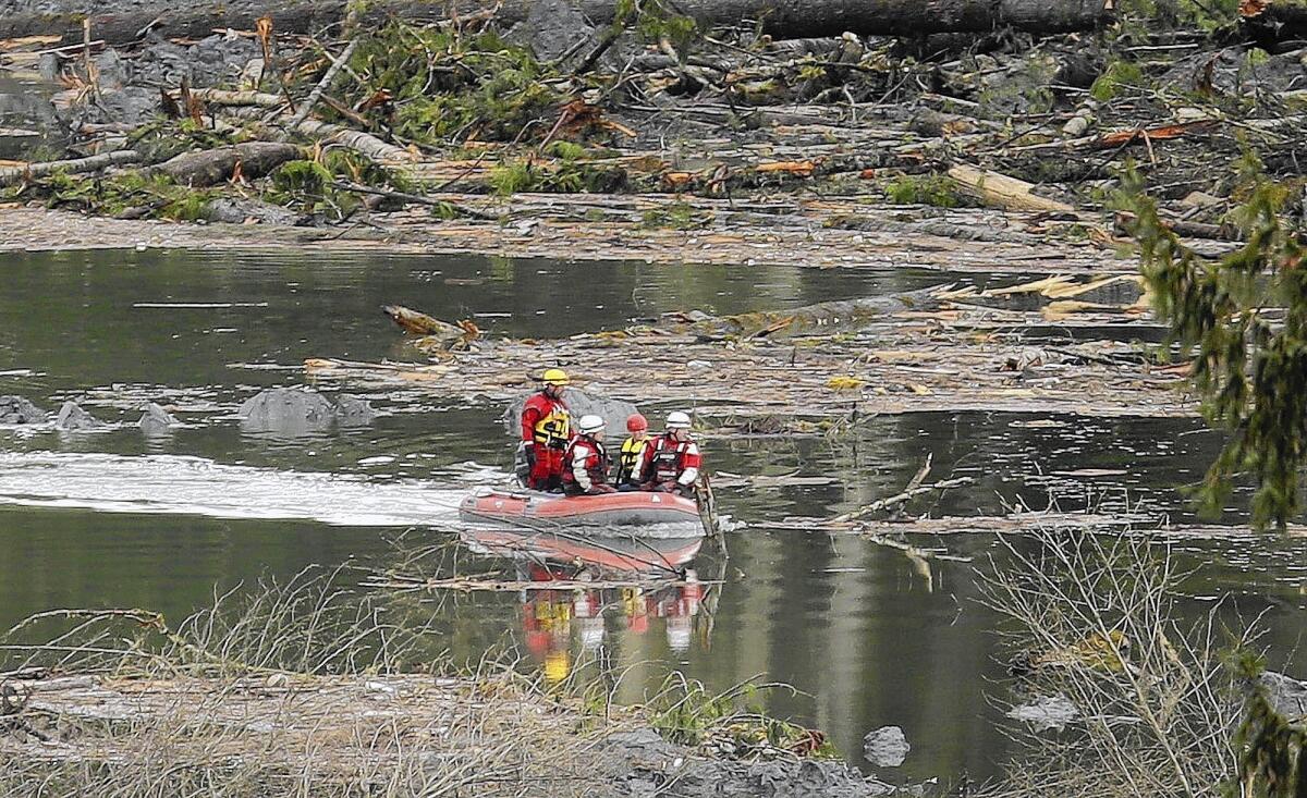 Search and rescue workers use a boat to move around the debris from the massive mudslide that struck Saturday in Oso, Wash.