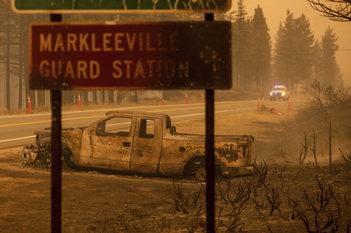 A scorched truck sits beyond a burned road sign.