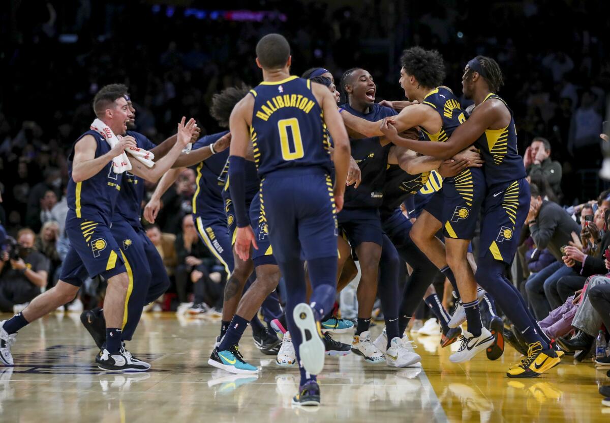 Teammates swarm Andrew Nembhard's (second from right) after his buzzer-beater three-pointer beats Lakers.