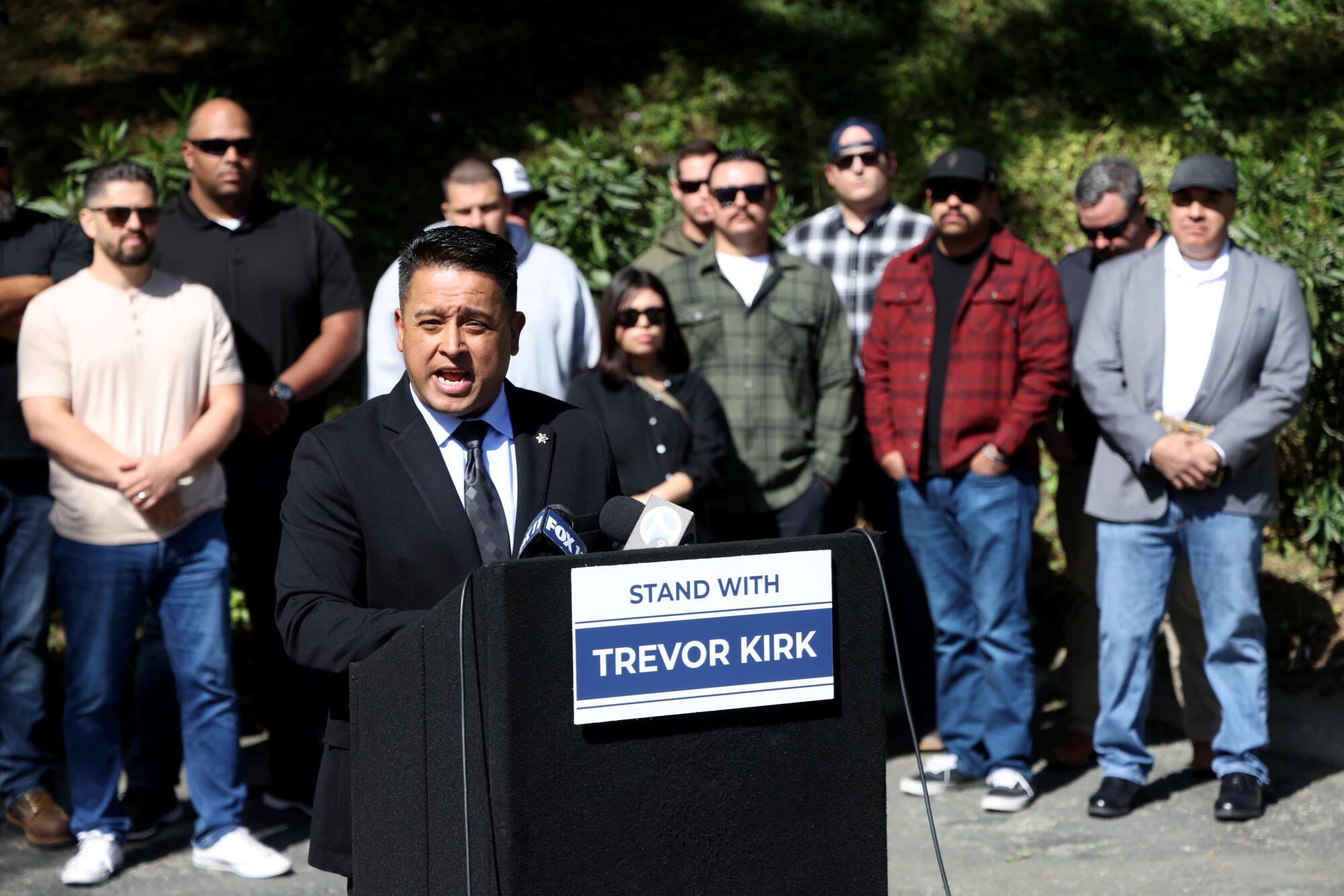 Cesar Romero of the Los Angeles Sheriffs' Professional Assn. speaks at a lectern with plainclothes deputies looking on.