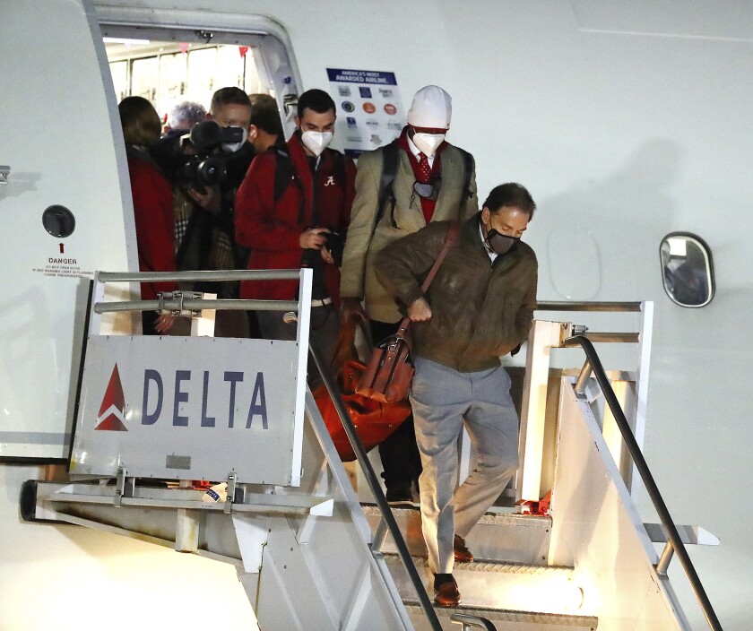 Alabama head coach Nick Saban, front, and his team get off an airplane during College Football Playoff championship team arrivals at Indianapolis Airport on Friday, Jan. 7, 2022, in Indianapolis. Alabama and Georgia are scheduled to play in the NCAA college championship game on Jan. 10. (Curtis Compton/Atlanta Journal-Constitution via AP)