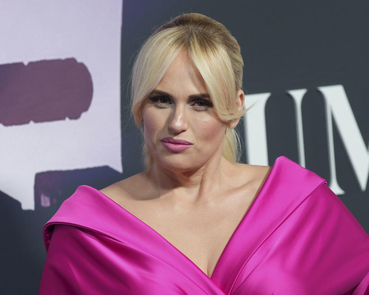 Rebel Wilson in a hot pink dress pursing her lips and tilting her head to left