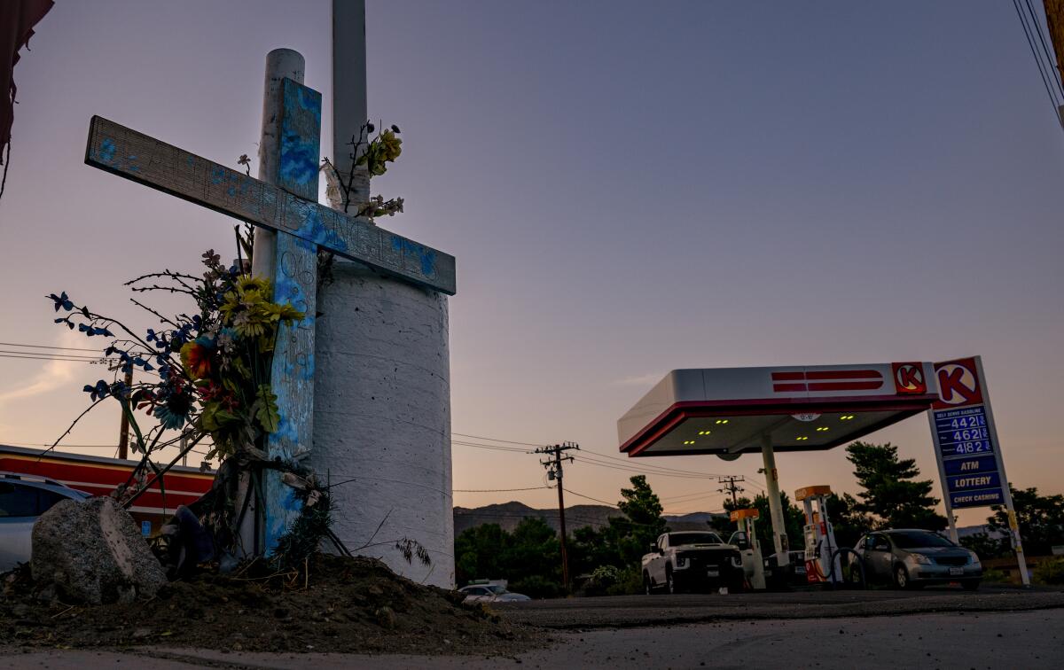 A makeshift cross still stands at a memorial by a gas station.