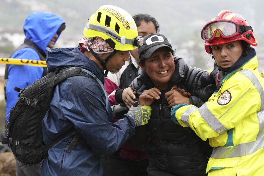 Rescue workers comfort a woman whose daughter is missing in Alausi, Ecuador, Tuesday, March 28, 2023, the day after a landslide swept through the town burying dozens of homes. (AP Photo/Dolores Ochoa)