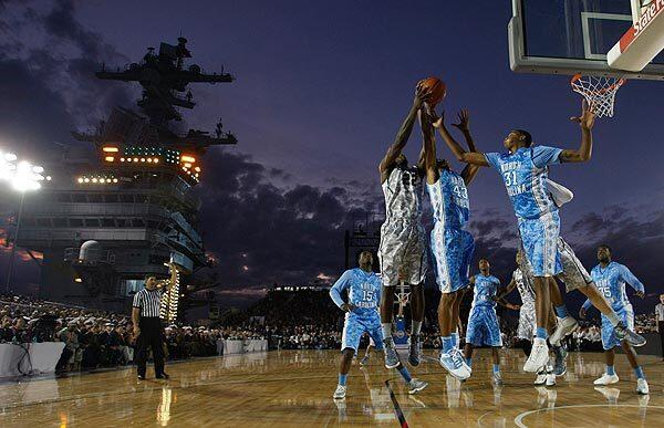 Michigan State's Branden Dawson, (22) battles Nor Carolina James Michael McAdoo (43) and John Henson (31) for a rebound under a twilight sky during the first half of the Carrier Classic on the flight deck of the aircraft carrier USS Carl Vinson.