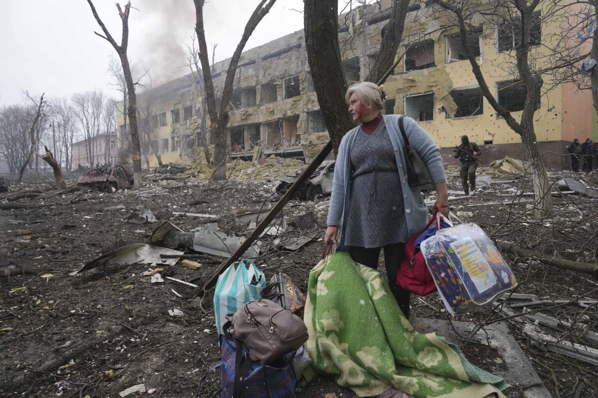 A woman walks outside the damaged by shelling maternity hospital in Mariupol, Ukraine, Wednesday, March 9, 2022. A Russian attack has severely damaged a maternity hospital in the besieged port city of Mariupol, Ukrainian officials say. (AP Photo/Evgeniy Maloletka)