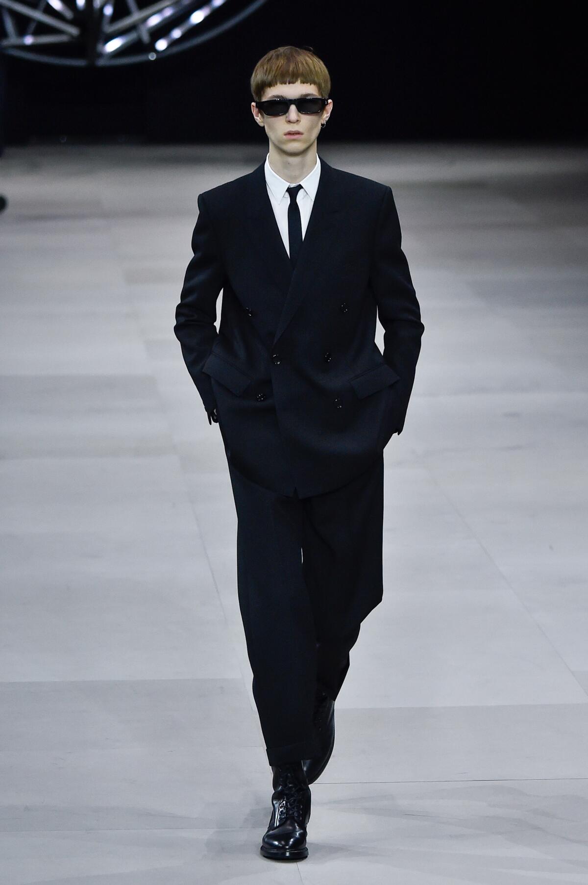 Un modelo camina por la pasarela durante el show de otoño/invierno de Celine Menswear en París a principios de este año. Un observador de la moda elogia a la diseñadora Hedi Slimane por “tomar una gabardina o esas gafas Ray-Ban que usaría tu padre y hacer que sea algo duro, futurista y raro”.