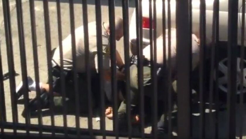 A video frame grab shows two Los Angeles County sheriff's deputies and 23-year-old Noel Aguilar struggle on the driveway of an apartment complex in Long Beach. Aguilar was shot and killed.