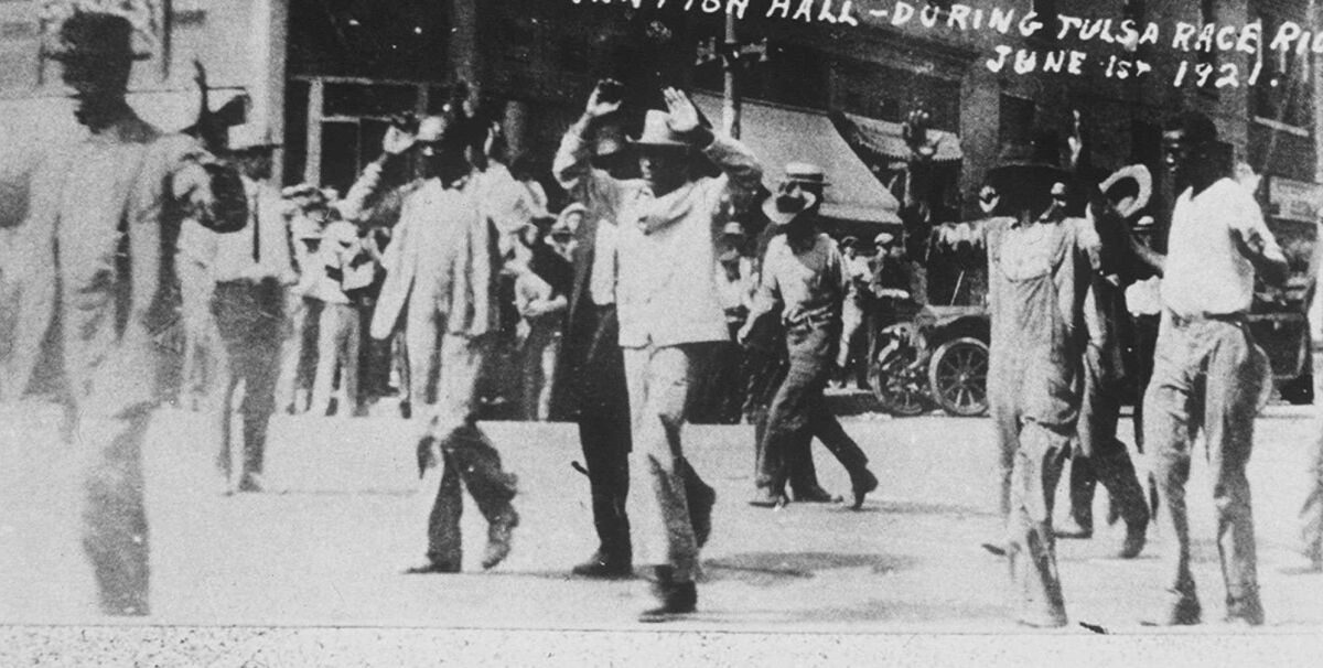 Black detainees walk with their hands up after the 1921 race massacre in Tulsa, Okla.