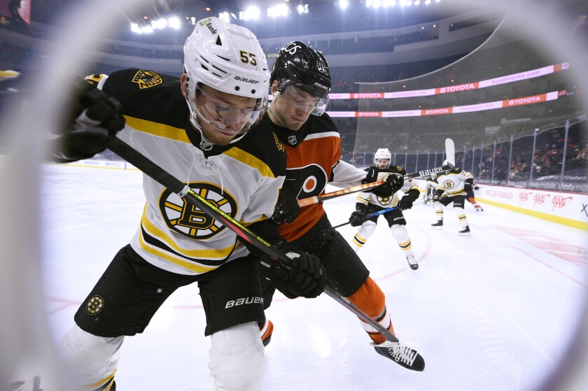 Boston Bruins' Jeremy Lauzon, left, and Philadelphia Flyers' Joel Farabee battle along the boards for the puck during the first period of an NHL hockey game, Saturday, April 10, 2021, in Philadelphia. (AP Photo/Derik Hamilton)
