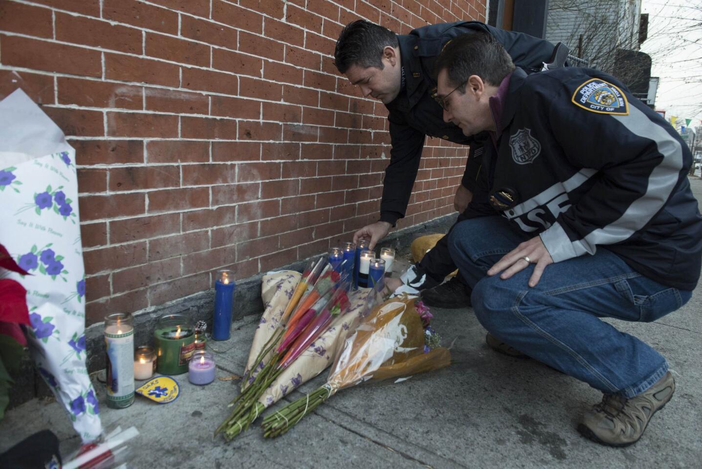 Police officers lay flowers at a makeshift memorial at the scene were two police officers were shot dead in the Brooklyn borough of New York