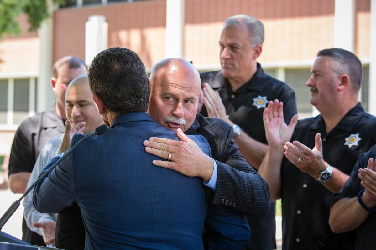 Fresno Police Chief Jerry Dyer hugs Antonio Villaraigosa after a 2018 news conference
