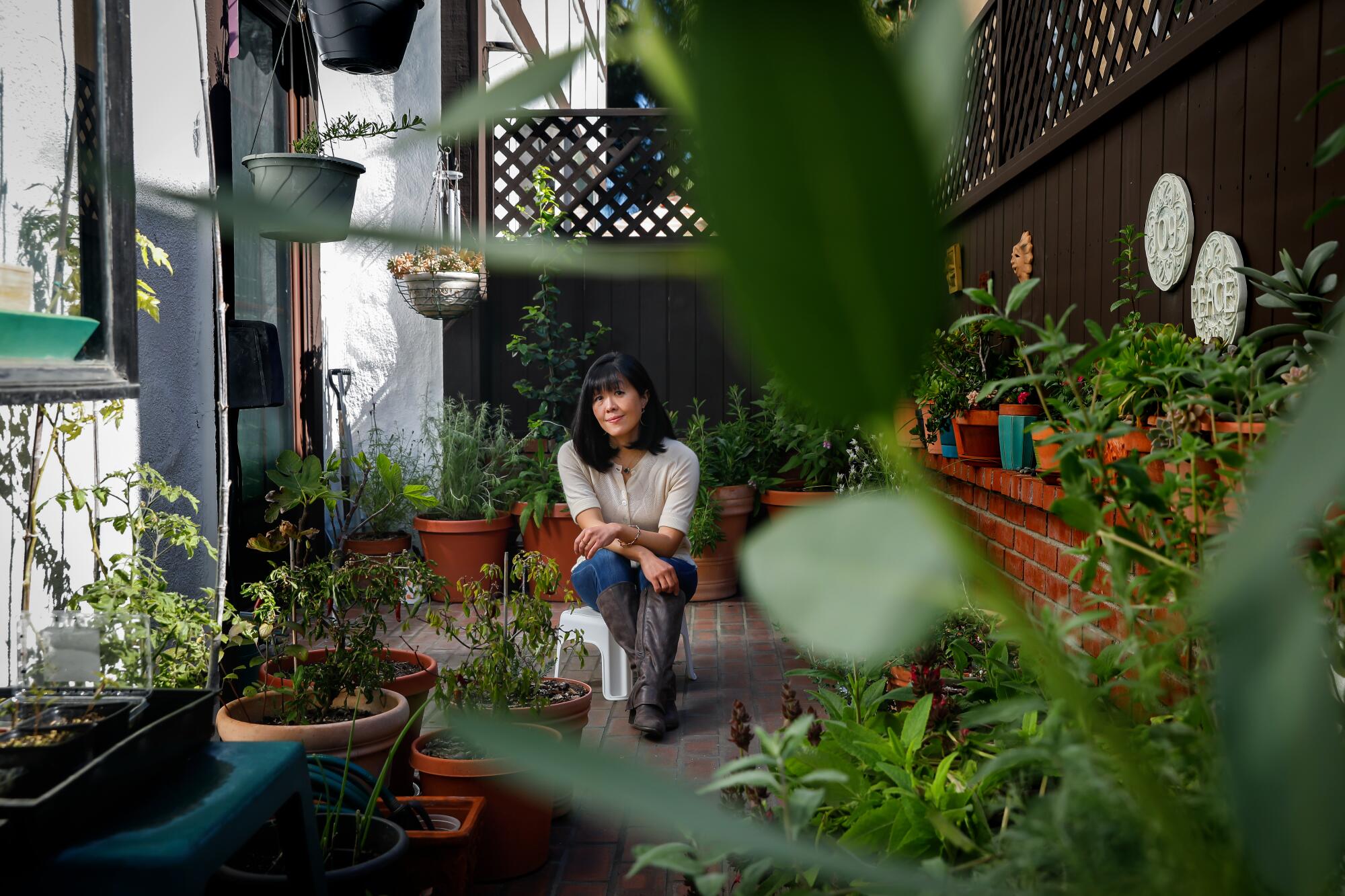 Barbara Chung sits on her townhouse terrace among her garden of California native plants.