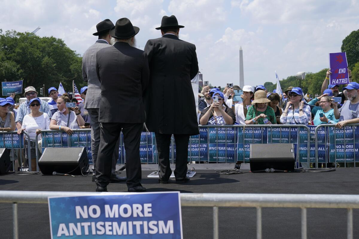 People stand on a stage in Washington near a "No more antisemitism" sign. 
