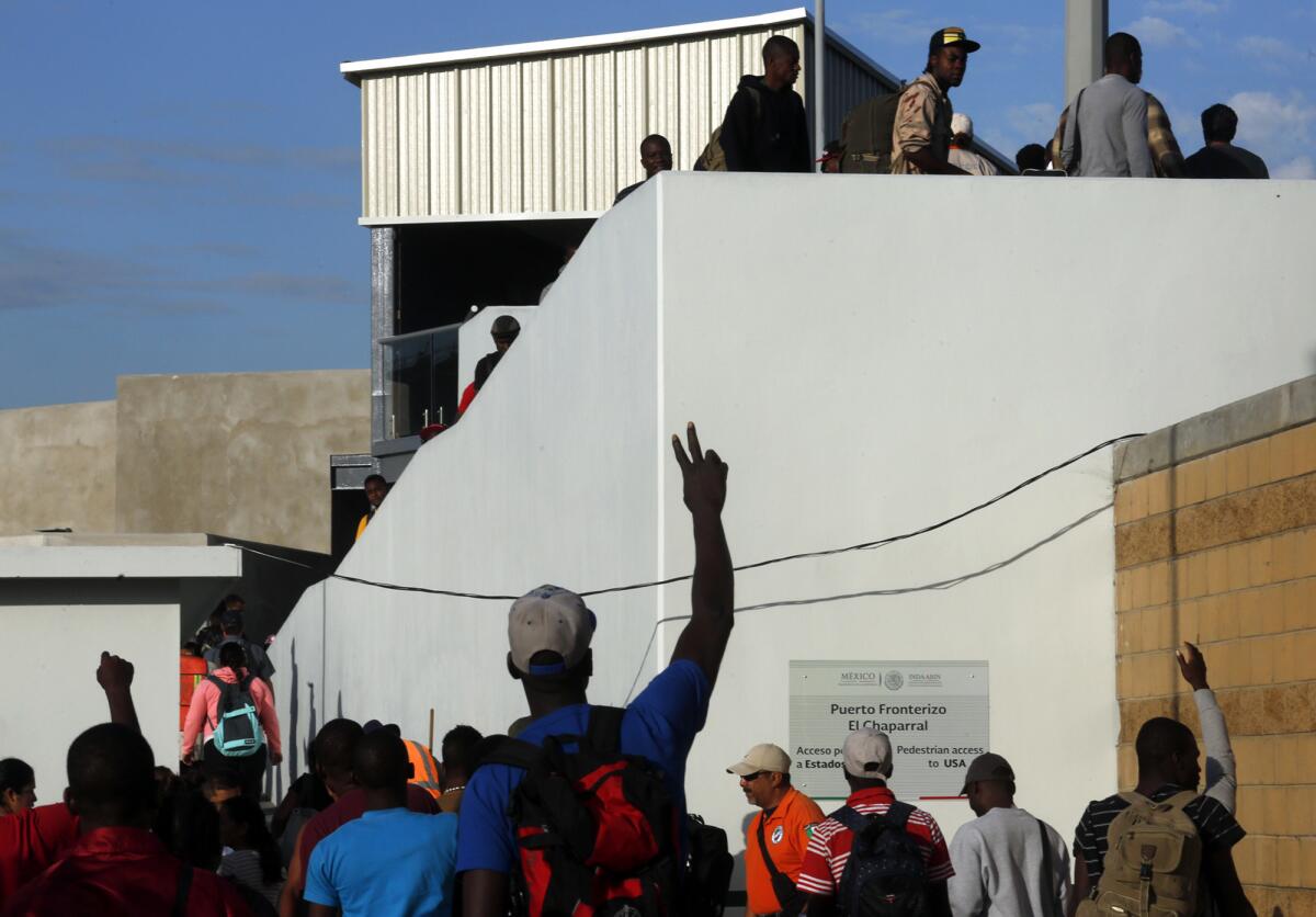 Migrants wave to their friends as they cross the pedestrian bridge leading from Tijuana, Mexico, to the United States.