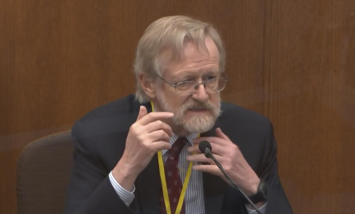 A man in glasses and a suit sits on witness stand in court