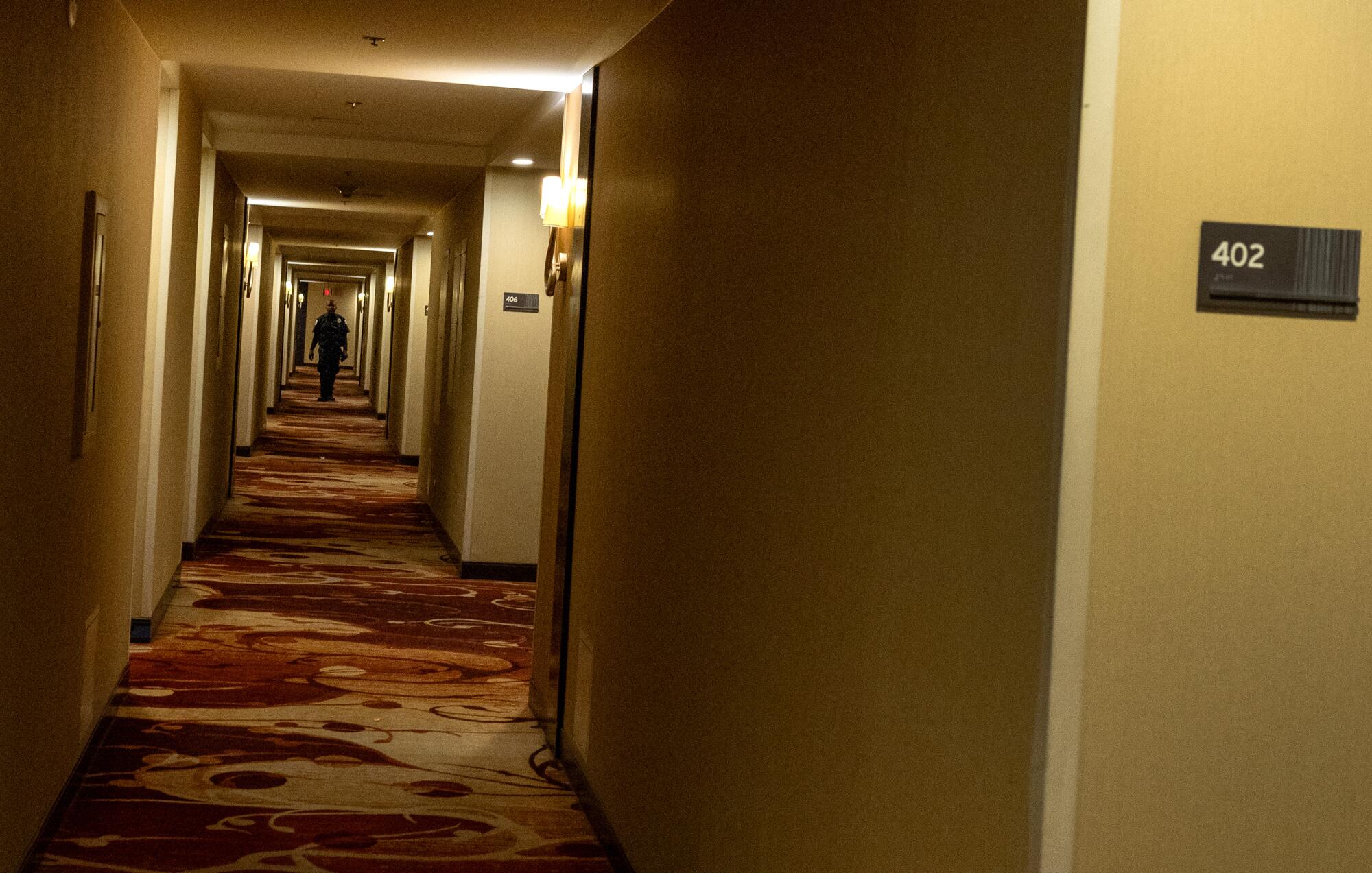 Security guards patrol the carpeted halls of the LA Grand Hotel.