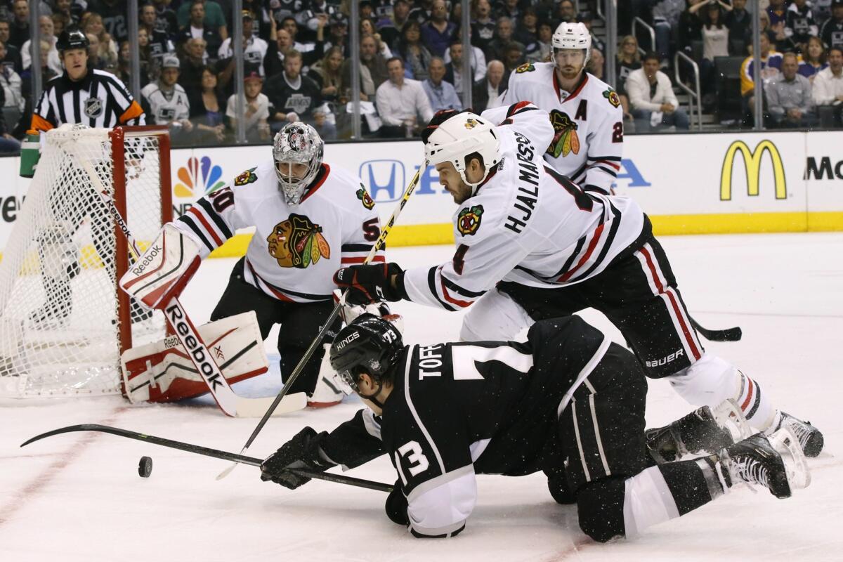 Kings forward Tyler Toffoli tries to pass the puck as he falls to the ice past Blackhawks defenseman Niklas Hjalmarsson in the first period of Game 6.