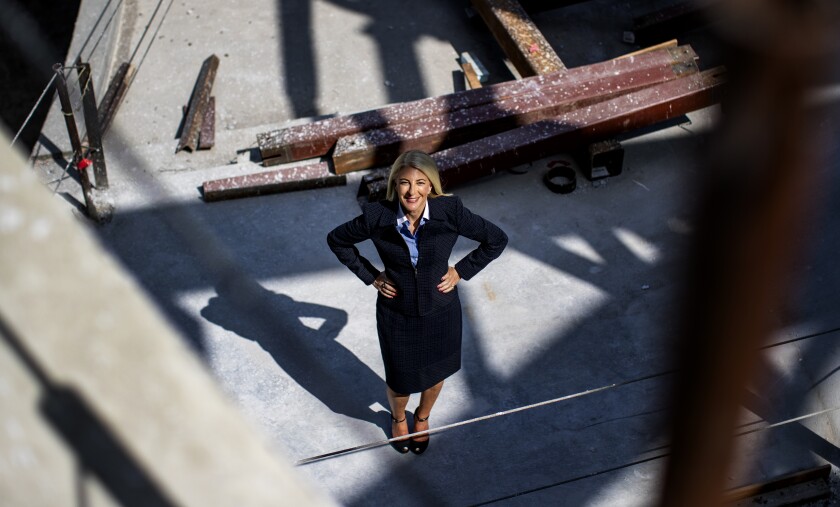 A woman in a business suit stands in a construction site.