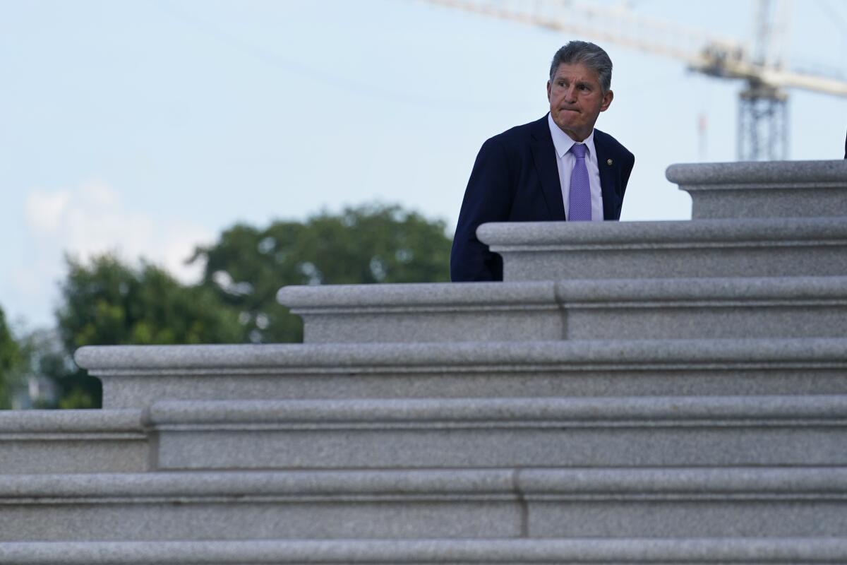 Sen. Joe Manchin, wearing a lavender tie, walks up the steps to the U.S. Capitol.