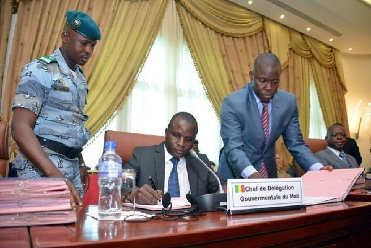 Col. Moussa Sinko Coulibaly, center, a Malian government minister, signs a peace agreement with Tuareg rebels Tuesday at a meeting in Ouagadougou, Bukino Faso.