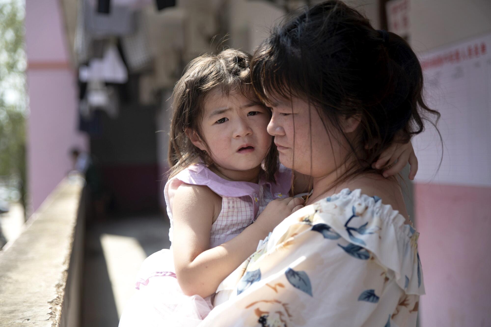 Mrs. Huang holds her daughter Huang Minfang, who is afraid of the floods.
