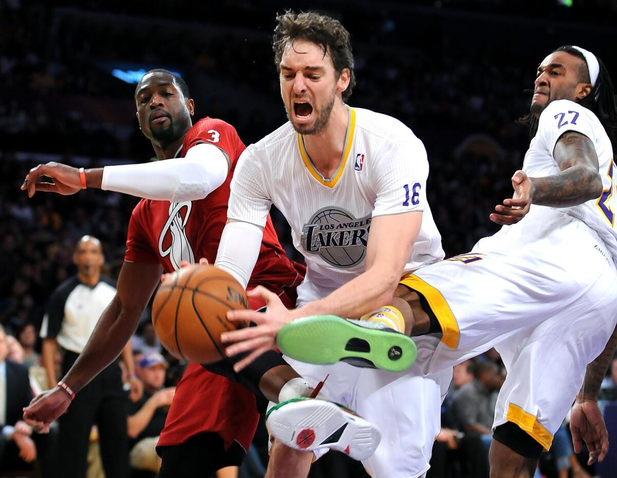 Lakers power forward Pau Gasol (16) is fouled by Heat guard Dwyane Wade during their Christmas Day game on Wednesday afternoon at Staples Center.