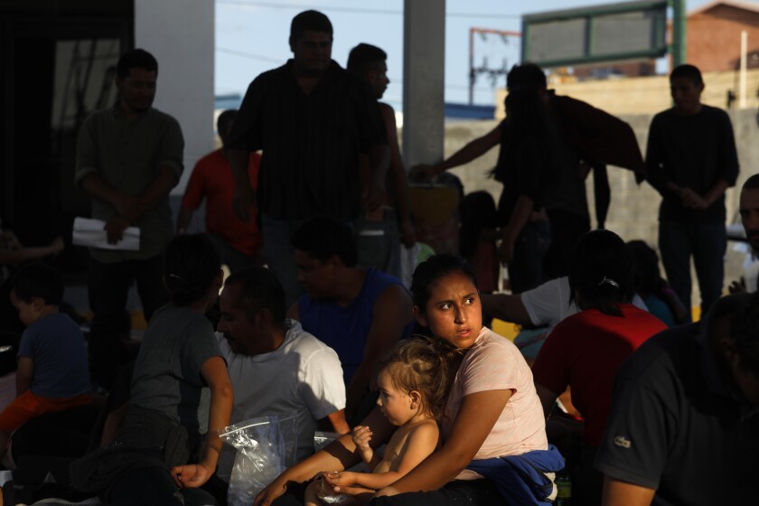 Asylum seekers wait in the parking lot of an immigration agency in Nuevo Laredo, Mexico