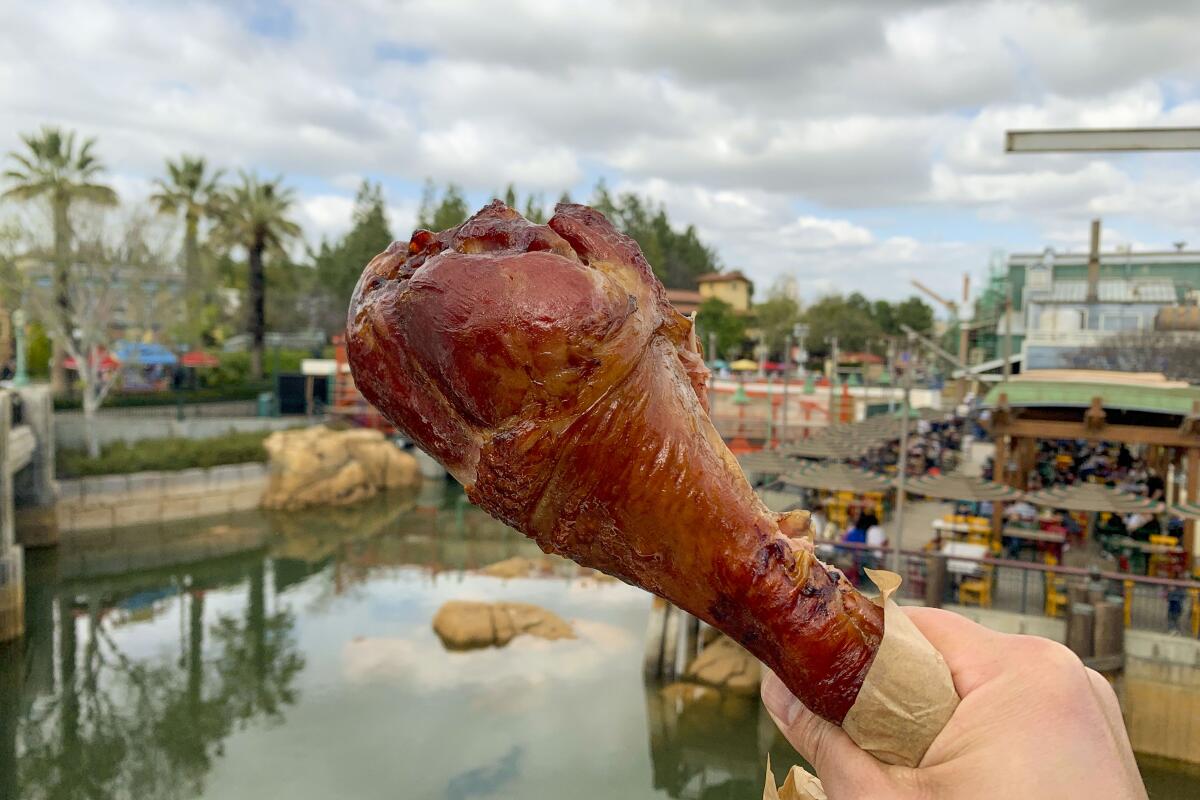 A hand holds up a jumbo smoked turkey leg at Poultry Palace
