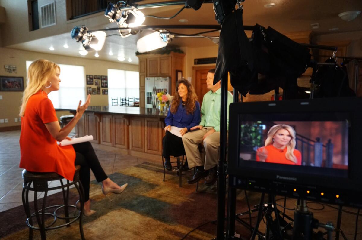 Megyn Kelly sits on a bench in a red dress and interviews Michelle and Jim Bob  Duggar.