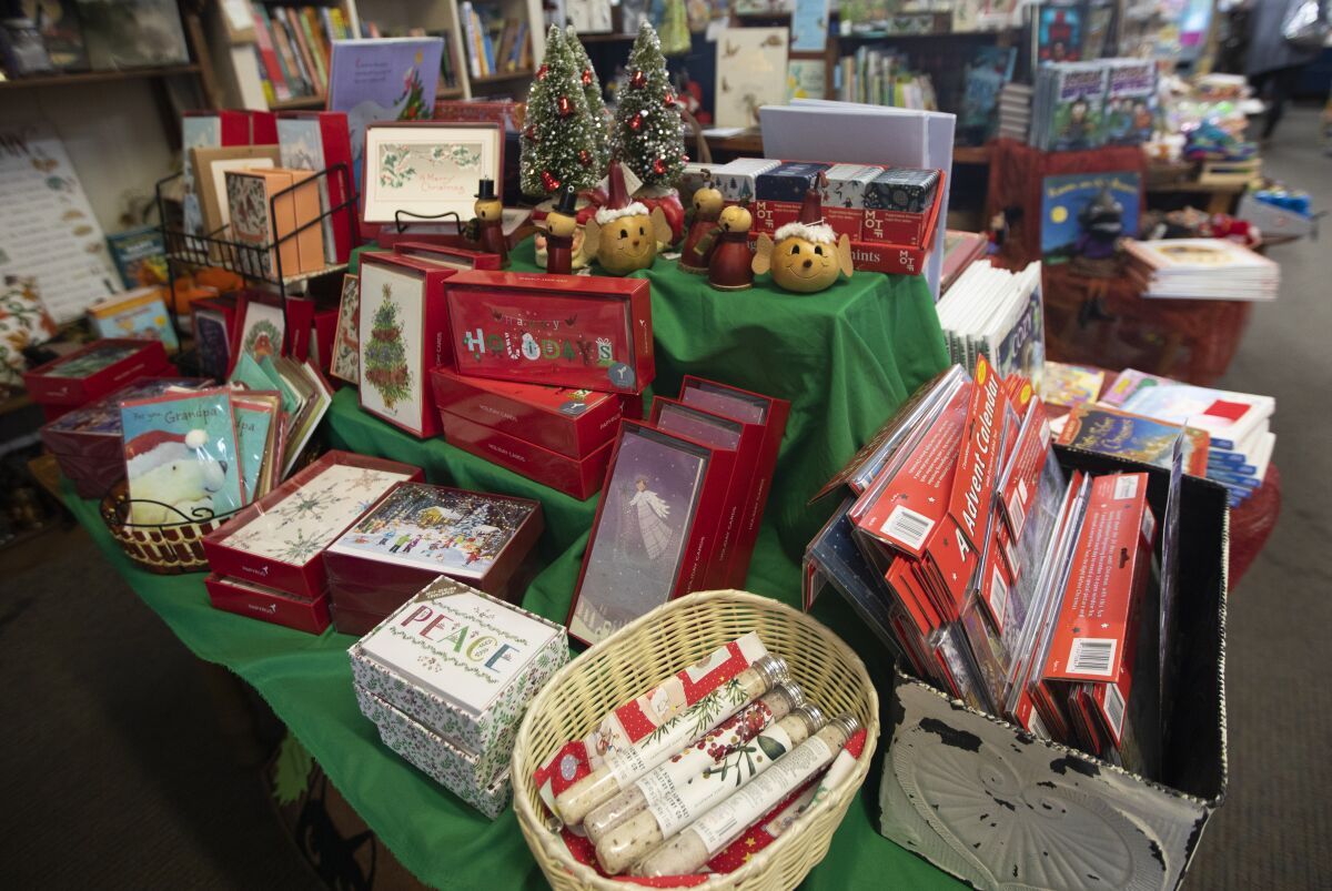 Holiday cards and toys are stacked on a table at Once Upon a Time bookstore.