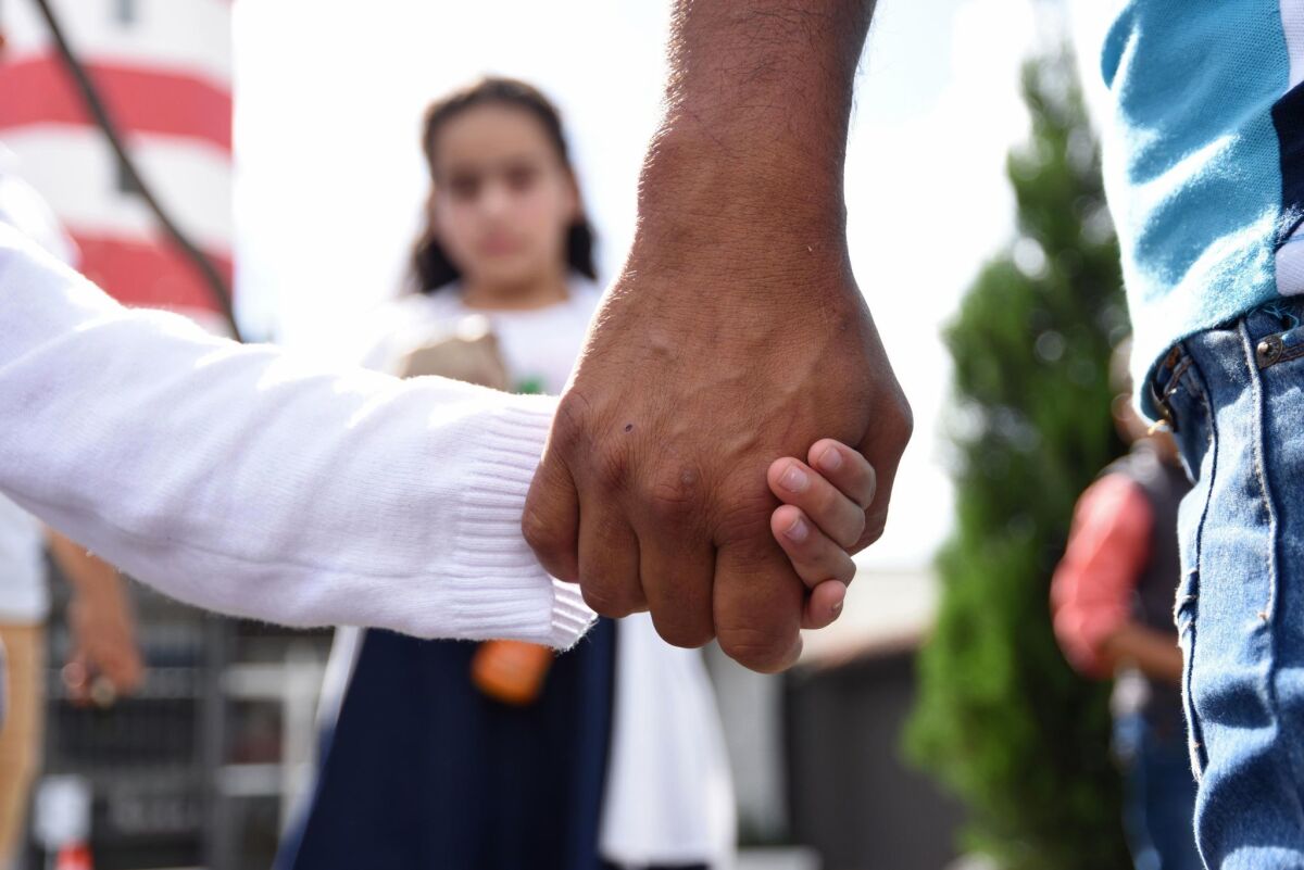 A man holds his daughter's hand after picking her and his wife up at an air base in Guatemala City on July 10, after they were deported from the United States.