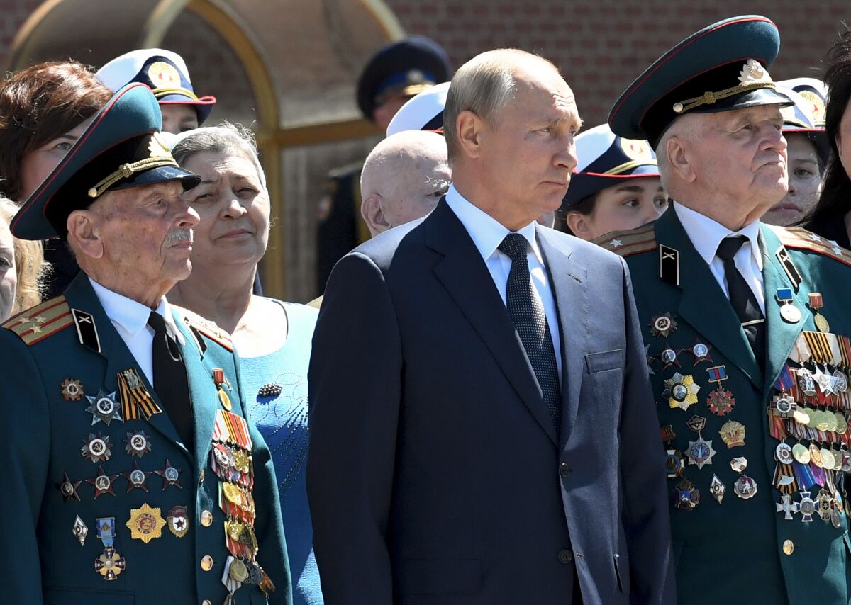 Russian President Vladimir Putin, center, stands between two WWII veterans as he takes part in a wreath laying ceremony at the Tomb of Unknown Soldier in Moscow, Russia, Monday, June 22, 2020, marking the 79th anniversary of the Nazi invasion of the Soviet Union. (Alexei Nikolsky, Sputnik, Kremlin Pool Photo via AP)