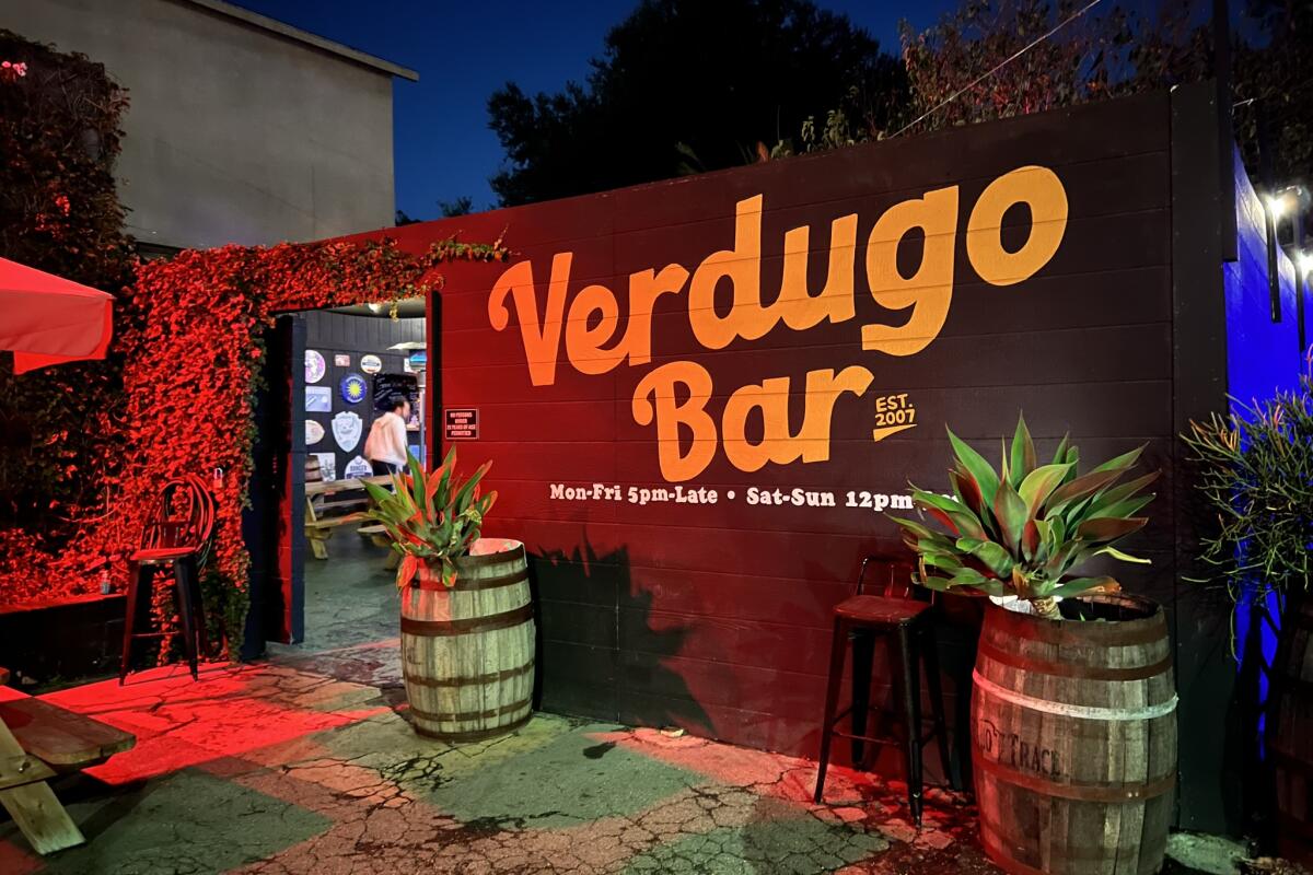 A brick wall seen at night painted with the words "Verdugo Bar." 