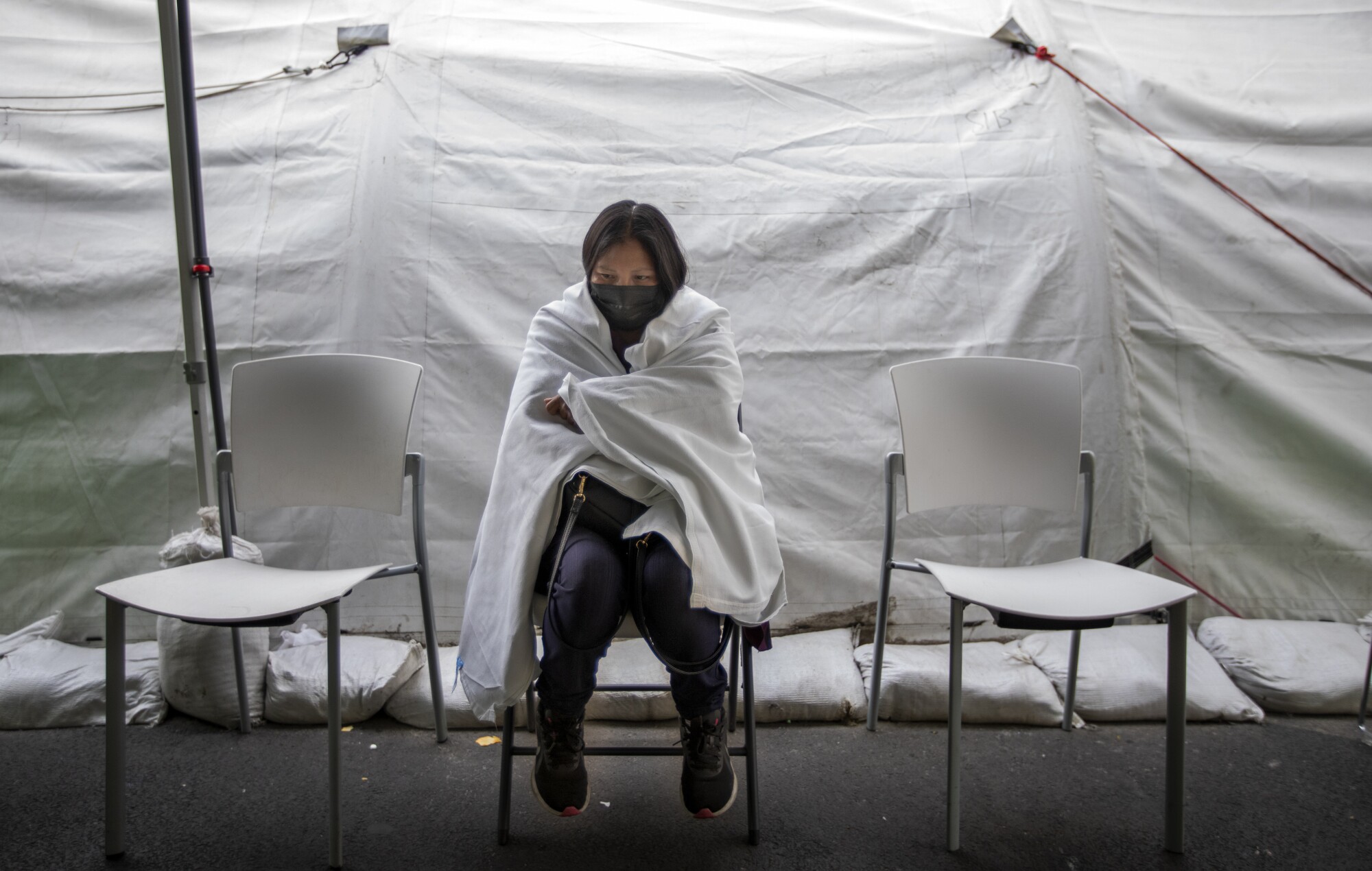 A patient sits in a blanket inside a tent