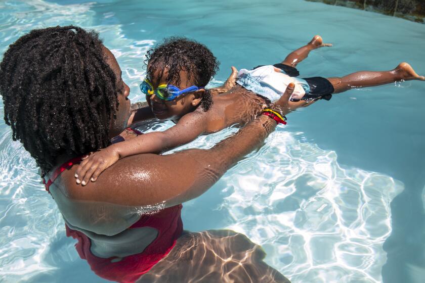 Los Angeles, CA - July 06: Swim teacher Symone Martin works with Sam Taylor, III, 2, during swim lessons with the Taylor siblings, including Harmony,10, and Melody,8, at a friends pool in the Baldwin Hills neighborhood of Los Angeles, CA, Tuesday, July 6, 2021. The Taylor siblings have been taking 35-40 minute lessons with Martin for about three weeks. Martin has been teaching swimming for almost six years and finds herself in this pool Monday through Saturday with lessons. (Jay L. Clendenin / Los Angeles Times)