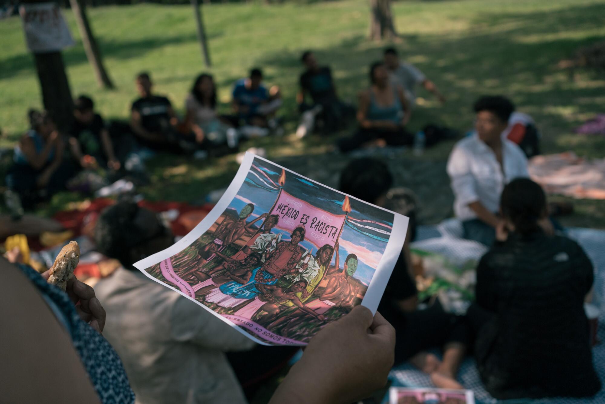 An attendee holds an illustration in a park setting