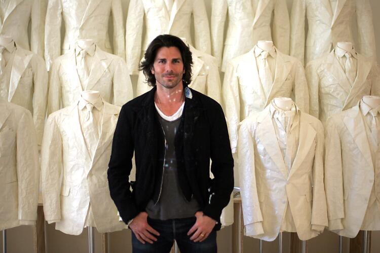 Artist Greg Lauren with white dinner jackets made from paper at his latest Los Angeles installation of men's clothing replicas created out of paper. He is designer Ralph Lauren's nephew.
