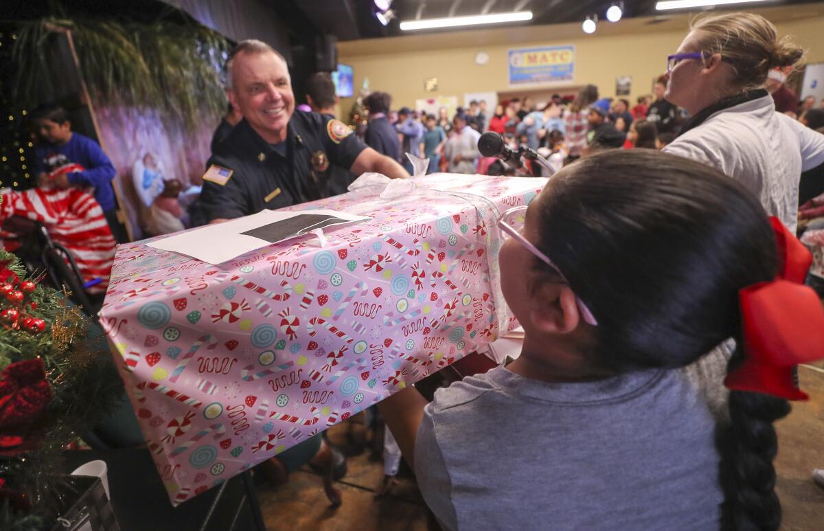 Heartland Fire and Rescue Fire Chief Steve Swaney hands Angelina Funez Limon, 10, her Christmas present.
