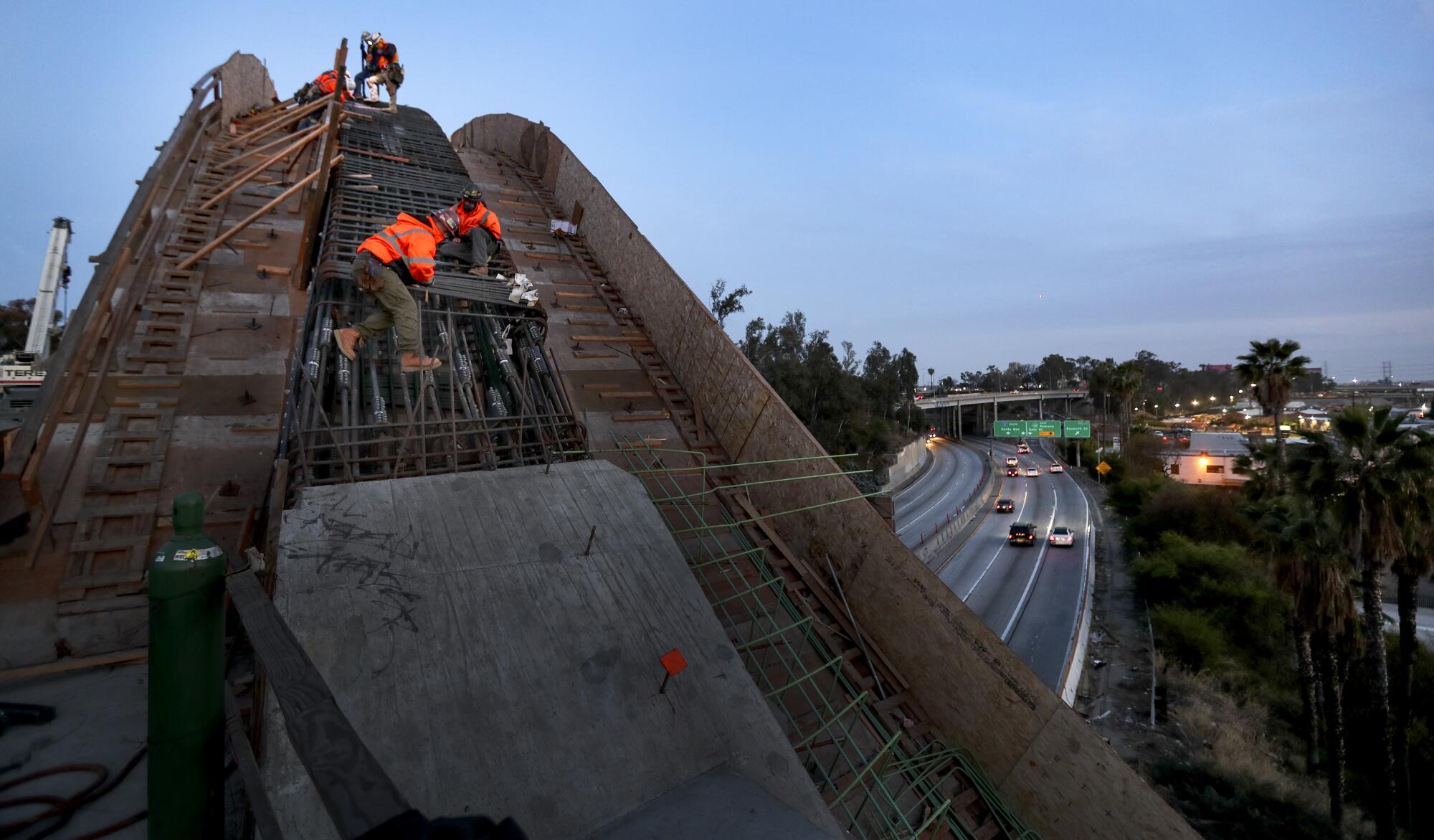 Traffic on the 101 Freeway whizzes by below as work continues on the new bridge