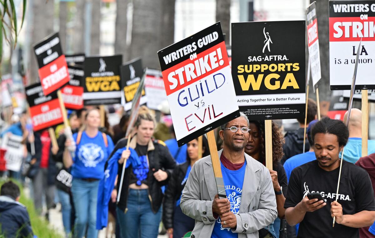 Writers on strike march with signs in front of Netflix in Hollywood