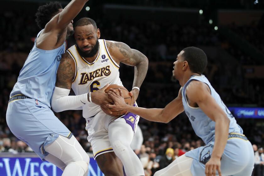 Los Angeles Lakers forward LeBron James, center, collides with Memphis Grizzlies forward Jaren Jackson Jr., left, as guard De'Anthony Melton, right, reaches for the ball during the second half of an NBA basketball game, Sunday, Jan. 9, 2022, in Los Angeles. (AP Photo/Alex Gallardo)